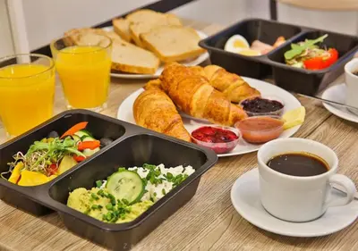 a table topped with trays of food and a cup of coffee at Aron Residence - by Upstairs in Kraków