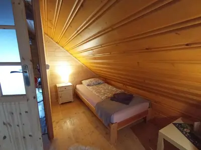 a small bedroom with a bed in a wooden ceiling at U Krysi in Kojszówka