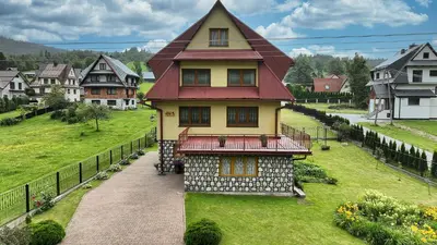 a yellow house with a red roof on a green field at Noclegi Obidowa-Pod Grapą in Obidowa