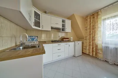 a kitchen with white cabinets and a sink and a window at Noclegi Obidowa-Pod Grapą in Obidowa
