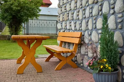 a wooden picnic table and bench next to a stone wall at Noclegi Obidowa-Pod Grapą in Obidowa