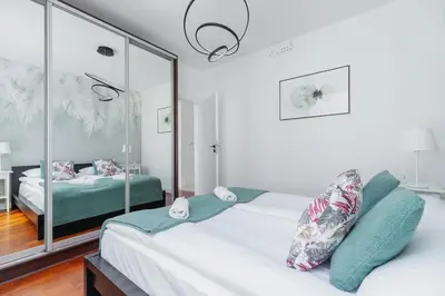 a white bedroom with a bed and a mirror at Apartment Łobzowska Cracow by Noclegi Renters in Kraków