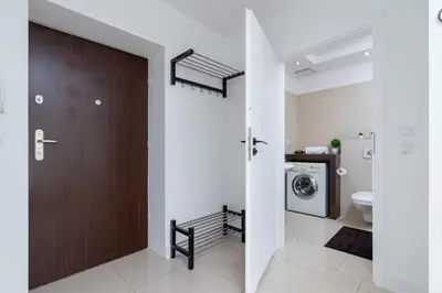 a bathroom with a wooden door and a washing machine at Apartment Łobzowska Cracow by Noclegi Renters in Kraków