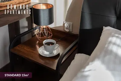 a cup of coffee on a table next to a bed at DOMINGO Elegant Rooms KRAKÓW Old Town in Kraków
