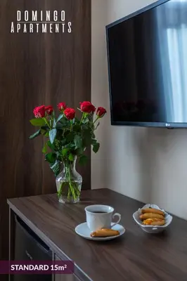 a table with a vase of roses and a cup of coffee at DOMINGO Elegant Rooms KRAKÓW Old Town in Kraków
