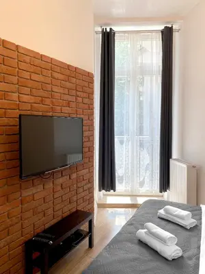 a bedroom with a brick wall with a flat screen tv at Starowiślna 41-43 by PI Apartments in Kraków