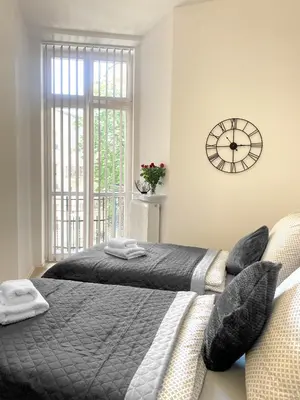 a bedroom with two beds and a clock on the wall at Starowiślna 41-43 by PI Apartments in Kraków