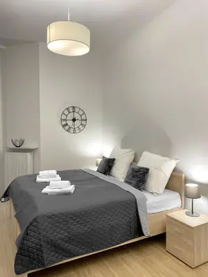 a bedroom with a large bed with a clock on the wall at Starowiślna 41-43 by PI Apartments in Kraków