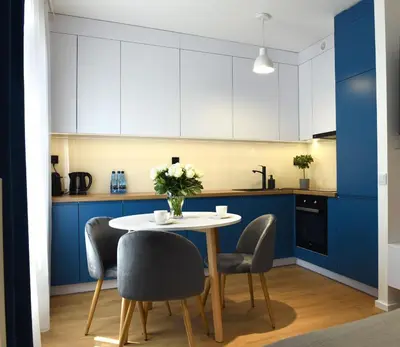 a kitchen with blue cabinets and a white table and chairs at Pearl Apartments-Kossak Residence Apartamenty w centrum Krakowa in Kraków