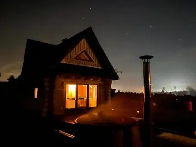 a small log cabin with a lit window at night at Bystry domek w Beskidach przy szlaku na Babią Górę in Bystra