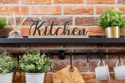 a kitchen sign hanging on a brick wall with potted plants at Old Town Studio Good Vibes by Noclegi Renters in Kraków