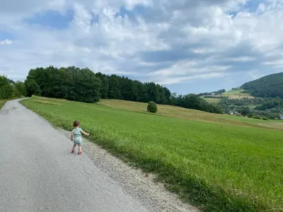 a little girl walking down a road next to a field at M37 x Fabryczna in Limanowa