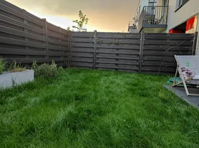 a wooden fence with two planters in the grass at Garden Apartment Self Check-in - Bezklucz kropka info in Kraków