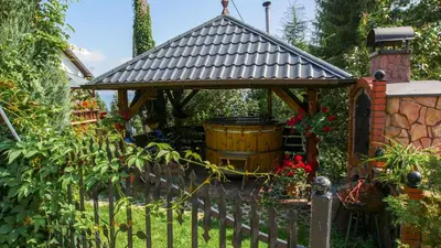 a wooden gazebo with a barrel in a garden at apartament simonka z jacuzzi zawoja in Zawoja