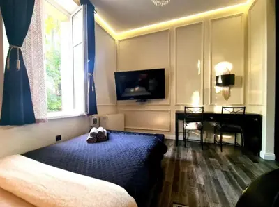 a bedroom with a bed and a desk and a window at Spa Bath Apartment in Kraków