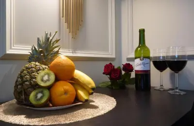 a bowl of fruit on a table with a bottle of wine at Spa Bath Apartment in Kraków