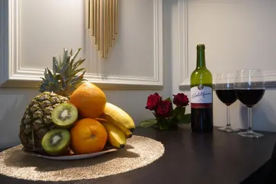 a bowl of fruit on a table with a bottle of wine at Spa Bath Apartment in Kraków