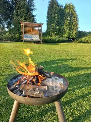 a fire pit in the grass with a bench in the background at Dom Pod Gaikiem in Łękawica