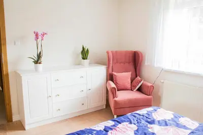 a bedroom with a pink chair and a white dresser at Dom Pod Gaikiem in Łękawica