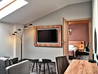 a living room with a table and a bedroom at 1891 Garni Hotel in Kraków