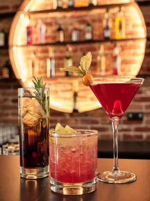 three cocktails sitting on top of a table at 1891 Garni Hotel in Kraków