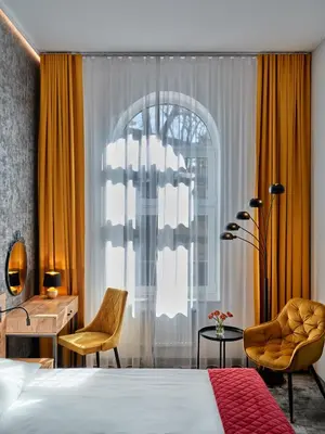 a bedroom with a bed and a desk and a window at 1891 Garni Hotel in Kraków