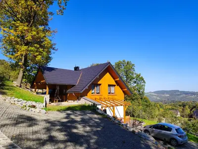 a house with a car parked in front of it at Domki nad Stawami in Ujanowice