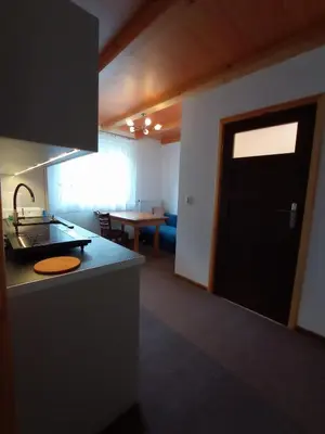 a kitchen with a black door and a living room at Noclegi Leśniczówka w Lanckoronie in Lanckorona