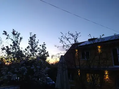 a building with the sunset in the background at Noclegi Leśniczówka w Lanckoronie in Lanckorona