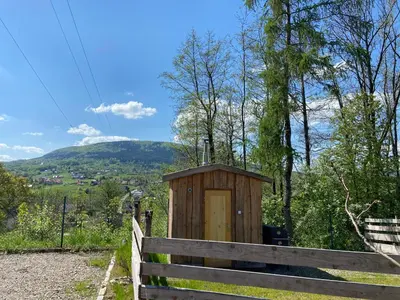 a wooden out house on a fence with a hill in the background at Rogate Domki in Zasań