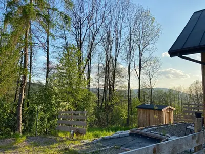 a backyard with a wooden fence and a shed at Rogate Domki in Zasań