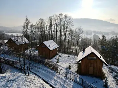 a group of wooden cabins in the snow at Rogate Domki in Zasań