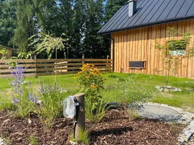 a garden in front of a wooden house at Rogate Domki in Zasań