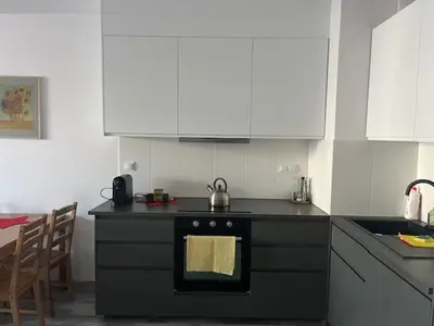 a kitchen with a black stove and white cabinets at APARTAMENT HELSINKI in Kraków