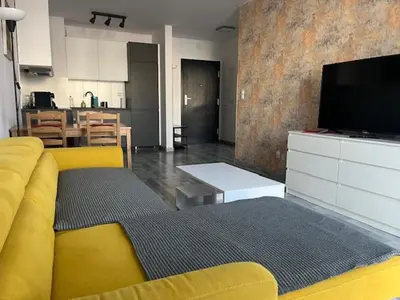 a living room with a yellow couch and a television at APARTAMENT HELSINKI in Kraków