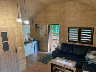 a living room with a couch and a kitchen at Chatka pod orzechem in Spytkowice
