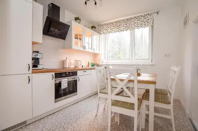 a kitchen with white cabinets and a table and chairs at Apartament w Alejce in Rabka