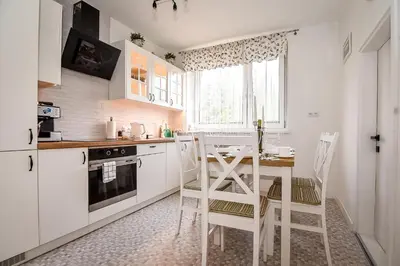 a kitchen with white cabinets and a table and chairs at Apartament w Alejce in Rabka