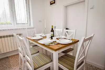 a dining room table with chairs and a bottle of wine at Apartament w Alejce in Rabka