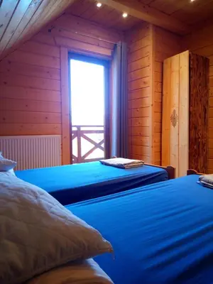 two beds in a wooden room with a window at Dom Słoneczna Chata Kasina Wielka in Kasina Wielka