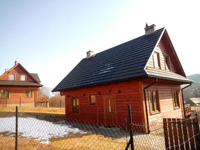 a small wooden house with a black roof at Dom Słoneczna Chata Kasina Wielka in Kasina Wielka