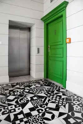 a green door in a building with a black and white floor at HOUSEHOST Apartment :Zacisze Street in Kraków