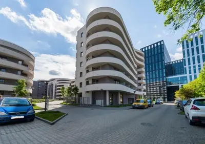 a building with cars parked in a parking lot at P&P Apartments in Kraków