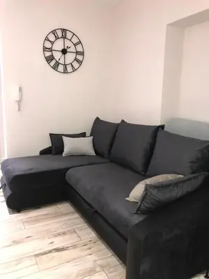 a black couch in a living room with a clock on the wall at Historic Old Town Kazimierz 2 Garden View in Kraków