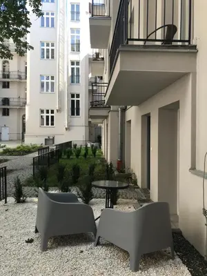 a patio with two chairs and a table in front of a building at Historic Old Town Kazimierz 2 Garden View in Kraków