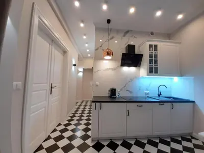 a kitchen with a sink and a black and white checkered floor at Cracowapart Hugo in Kraków