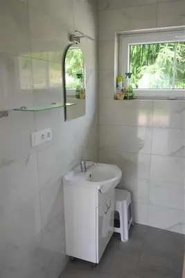 a white bathroom with a sink and a window at Domki pod Groniem in Kasina Wielka