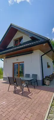 a picnic table and chairs in front of a house at Domki pod Groniem in Kasina Wielka