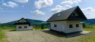 two small houses in a field with mountains in the background at Domki pod Groniem in Kasina Wielka