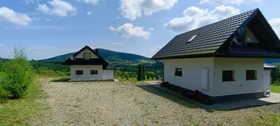 a small house with a black roof on a field at Domki pod Groniem in Kasina Wielka